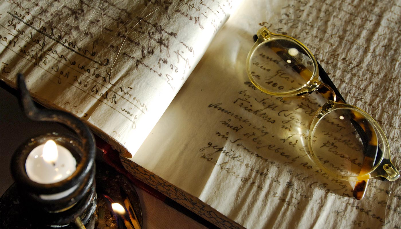 Dettaglio di un paio di occhiali appoggiati sopra un antico libro